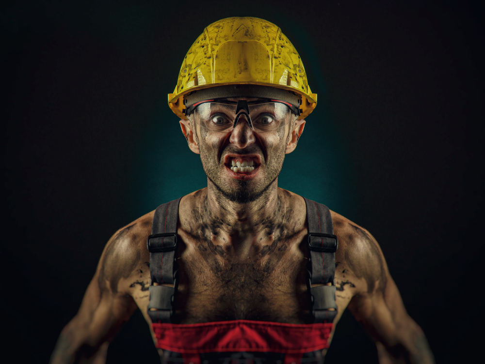 A Man Miner In A Worker S Clothes And A Helmet, Dirty, In Soot, With A Naked Body, Grimaces At The Camera